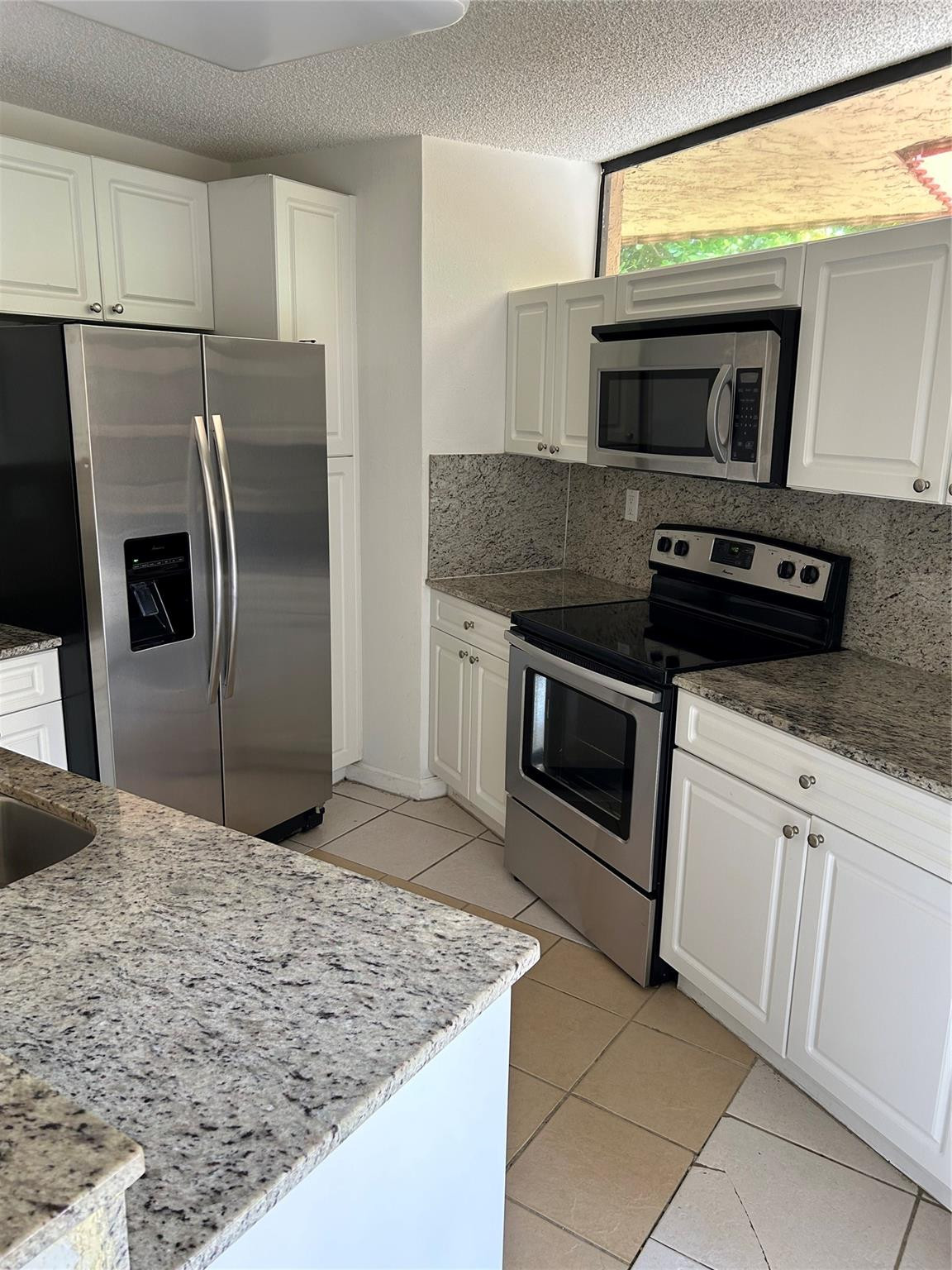 8117 Severn Drive, Unit C Boca Raton, FL 33433 - Photo 3 of 11 a kitchen with granite countertop a sink stove and refrigerator