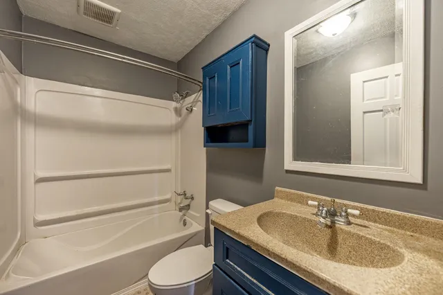 a bathroom with a granite countertop sink toilet and shower