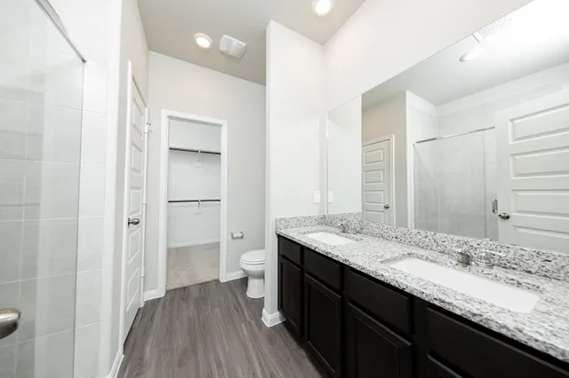 a bathroom with a granite countertop sink a toilet and shower