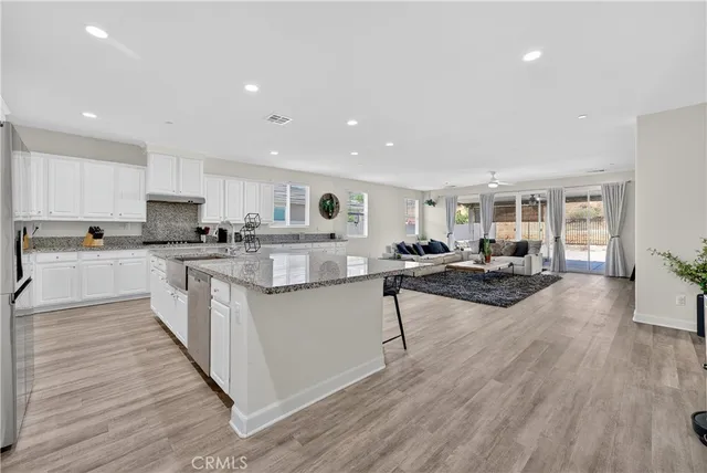 a kitchen with counter top space a sink wooden floor and view living room