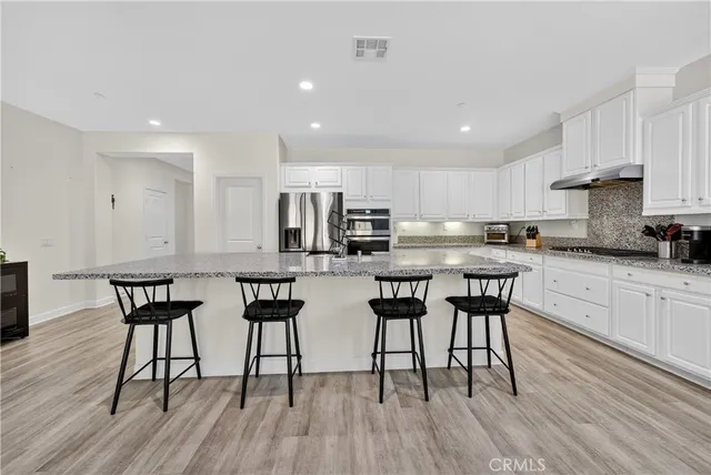 a kitchen with stainless steel appliances a table chairs refrigerator and cabinets