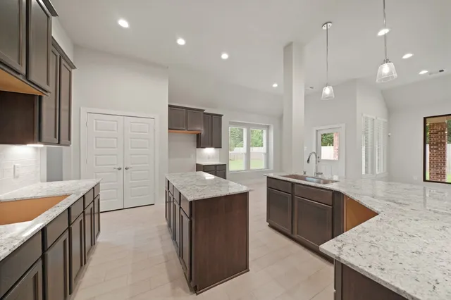 a kitchen with granite countertop kitchen island a sink appliances and a counter top space