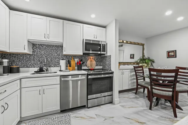 a kitchen with white cabinets and appliances