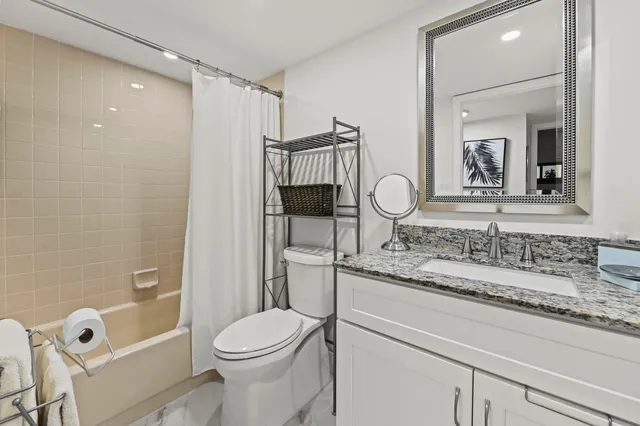 a bathroom with a granite countertop sink a toilet and shower