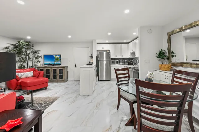a kitchen with stainless steel appliances kitchen island granite countertop a table chairs in it and wooden floors