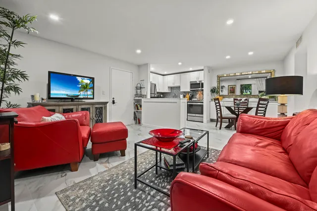 a living room with furniture kitchen view and a flat screen tv