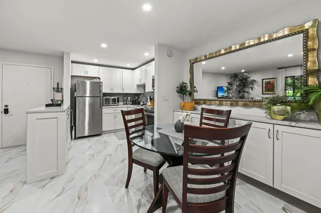 a kitchen with stainless steel appliances a dining table chairs and white cabinets