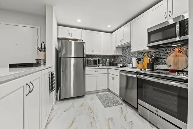 a kitchen with granite countertop a refrigerator stove and microwave