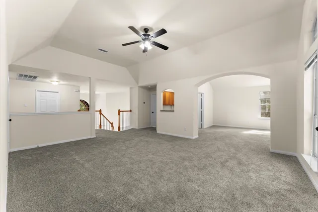 an empty room with chandelier fan and windows