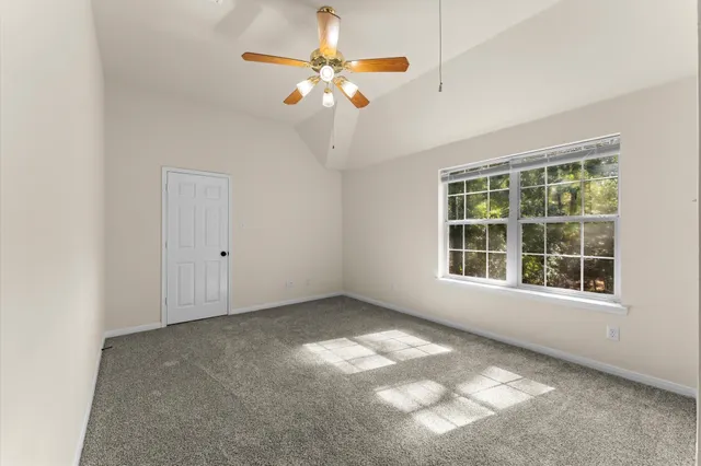 an empty room with chandelier fan and windows