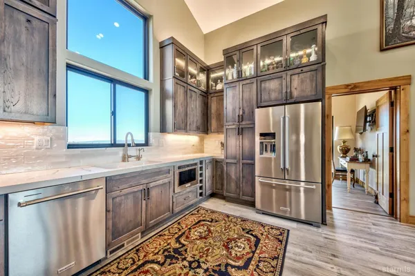 a kitchen with stainless steel appliances granite countertop a refrigerator a sink and a stove with wooden floor