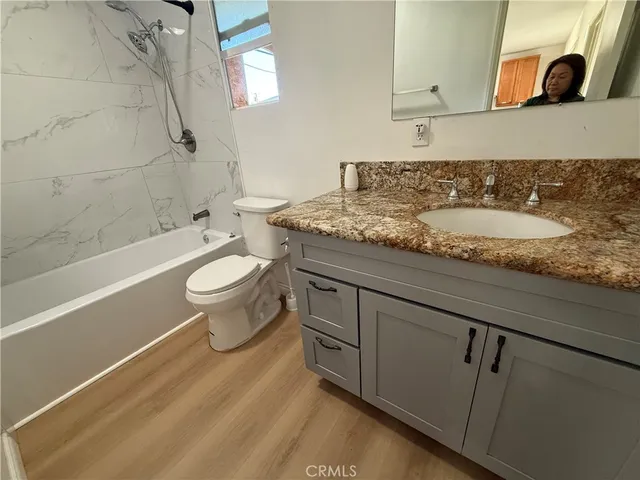 a bathroom with a granite countertop sink toilet mirror and bathtub