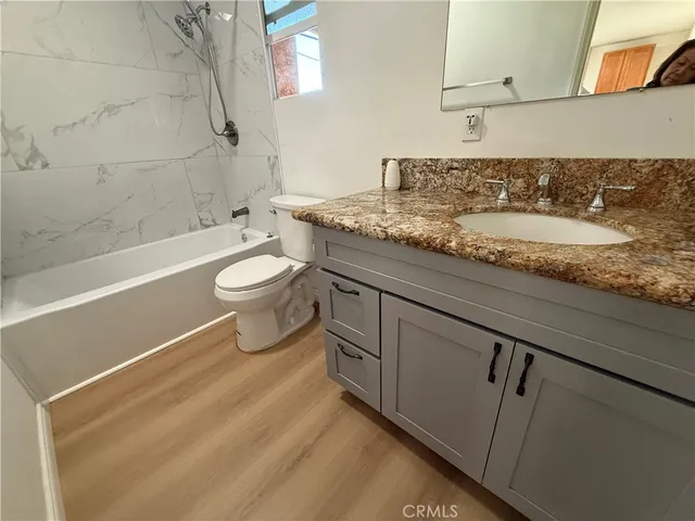 a bathroom with a granite countertop sink a toilet and bathtub