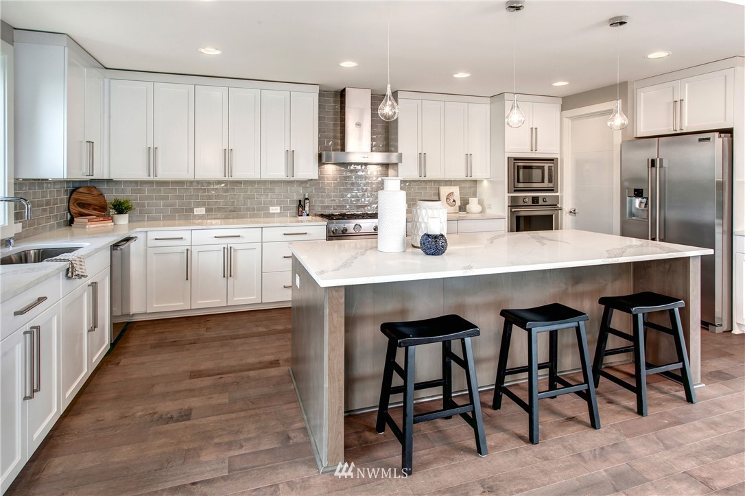 1002 North 30th Street Renton, WA 98056 - Photo 8 of 25 a kitchen with stainless steel appliances granite countertop a table chairs sink refrigerator and cabinets