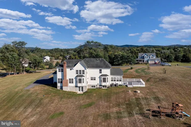 a view of a white house with a big yard and large trees