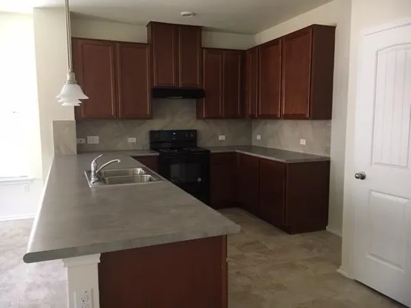 a kitchen with granite countertop a sink a stove and cabinets