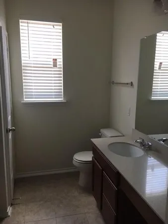 a bathroom with a granite countertop toilet a sink and a window