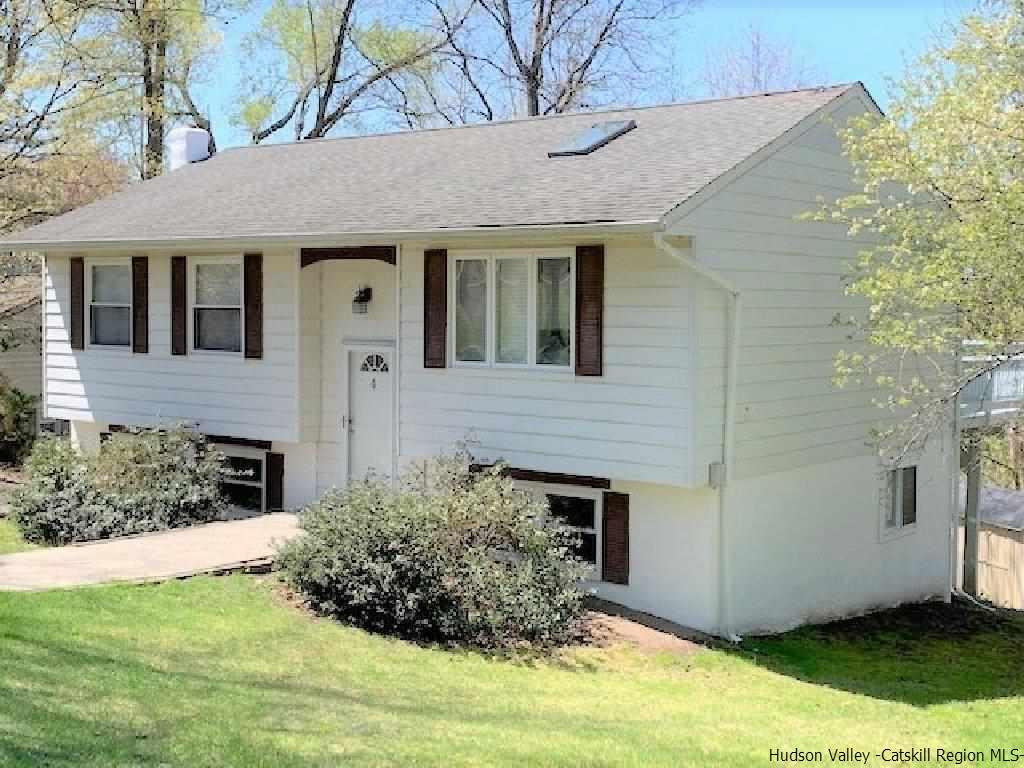 a view of a white house with a small yard and large tree