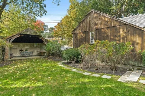 a backyard of a house with table and chairs under an umbrella