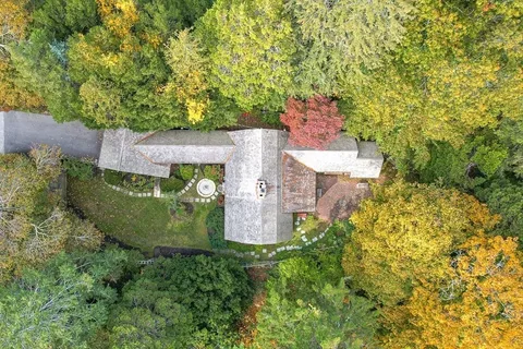 an aerial view of a house with a yard and trees all around