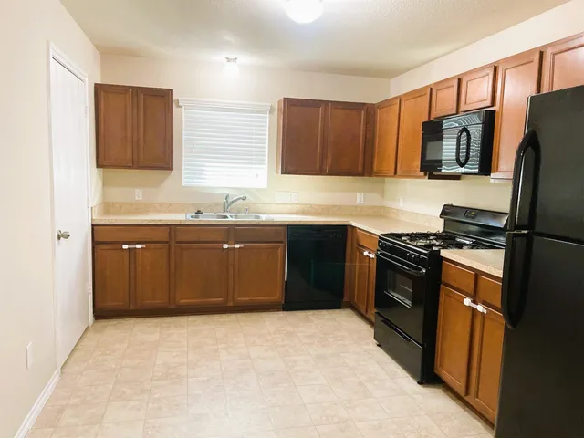 a kitchen with stainless steel appliances granite countertop a stove top oven a sink dishwasher a refrigerator and a microwave