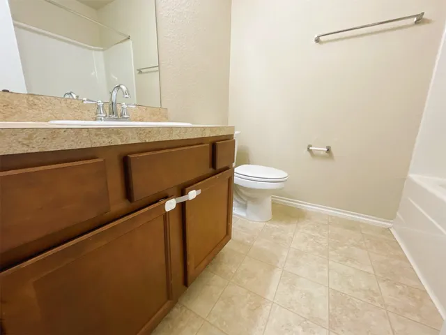 a bathroom with a granite countertop sink a toilet and a mirror