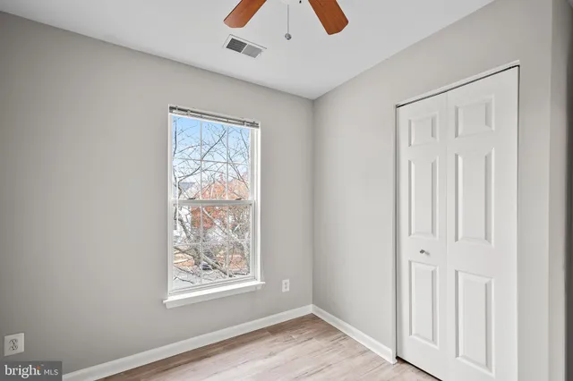 a view of an empty room with window and wooden floor