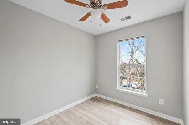 an empty room with windows and fan