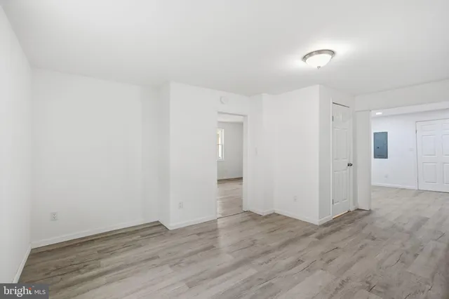 a view of an empty room with wooden floor and closet