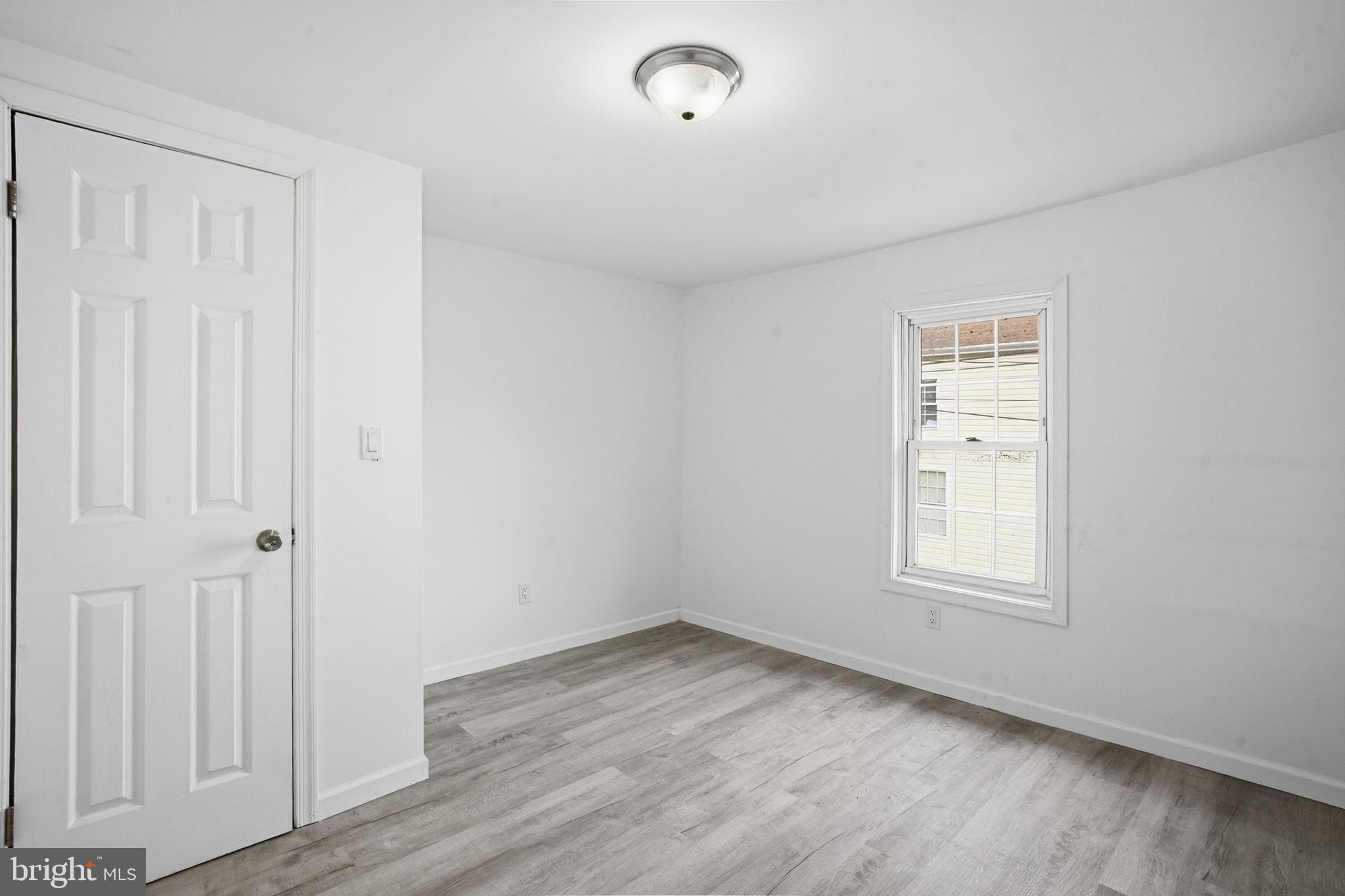 603 Academy Street Cambridge, MD 21613 - Photo 18 of 22 an empty room with wooden floor and windows