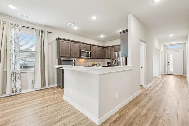 a kitchen with stainless steel appliances granite countertop a refrigerator a stove and a sink with wooden floor