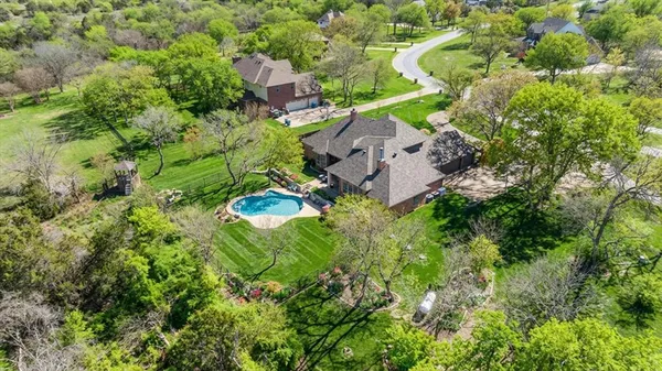 an aerial view of residential house with outdoor space and trees all around