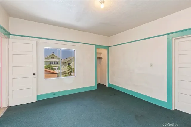 an empty room with windows and refrigerator