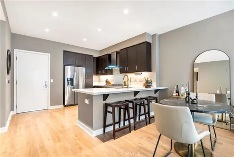 a kitchen with stainless steel appliances kitchen island granite countertop a dining table chairs and a refrigerator