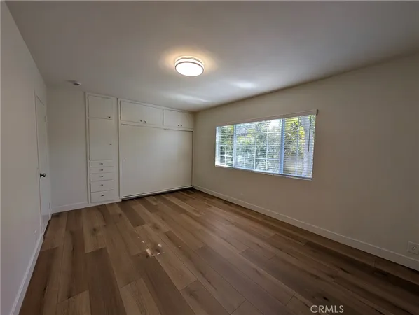 an empty room with wooden floor a ceiling fan and windows