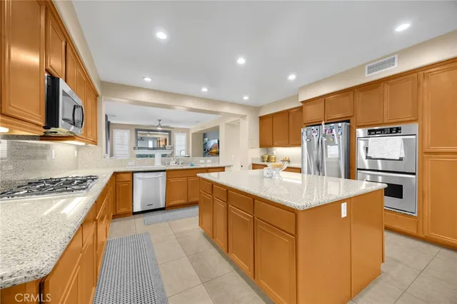 a kitchen with stainless steel appliances granite countertop a refrigerator a sink dishwasher a oven with white cabinets and wooden floor