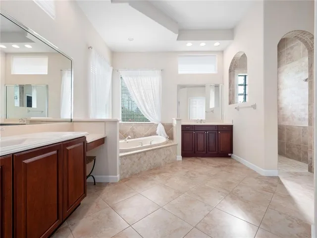 a spacious bathroom with a granite countertop double vanity sink a mirror and a bathtub