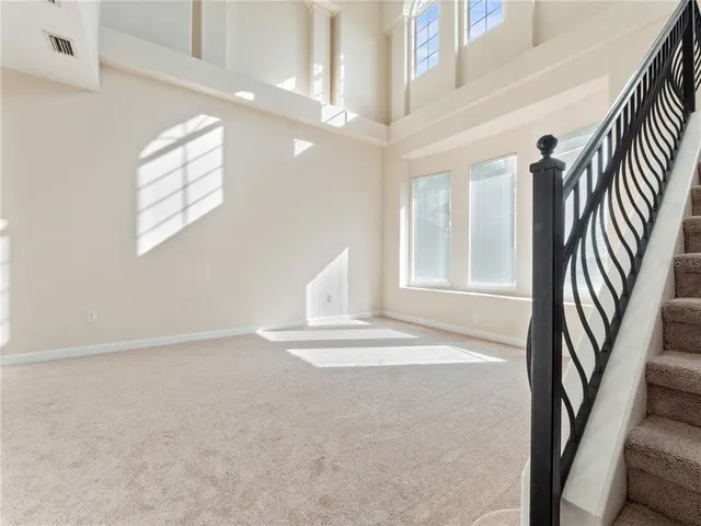 an empty room with windows and chandelier fan