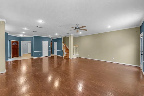an empty room with wooden floor and chandelier