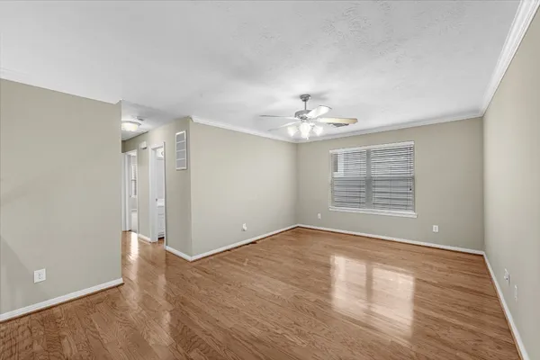 a view of an empty room with wooden floor and a window
