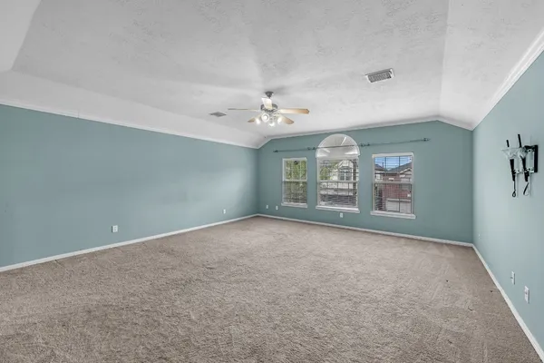 an empty room with windows and ceiling fan