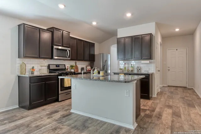 a kitchen with kitchen island granite countertop stainless steel appliances cabinets a sink and a counter top space