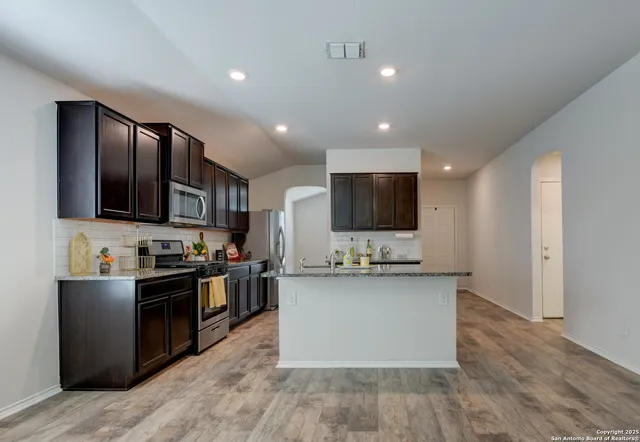 a kitchen with stainless steel appliances kitchen island granite countertop a stove top oven and sink