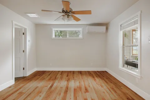 a view of empty room with wooden floor and fan