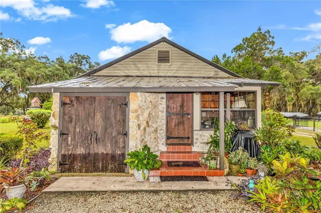 an aerial view of a house with garden space and trees all around