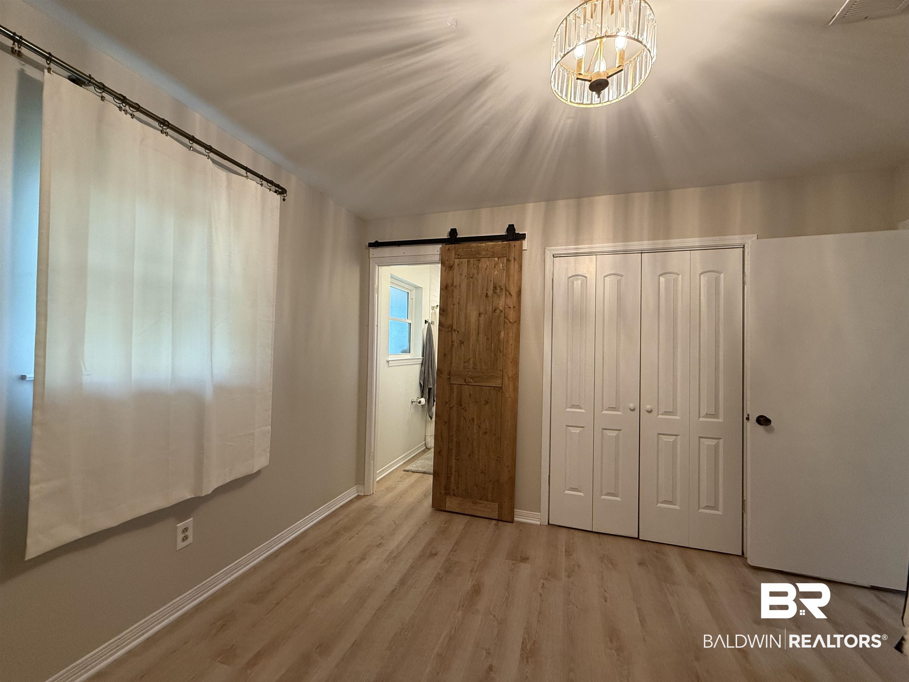 90 Florida Street Monroeville, AL 36460 - Photo 27 of 31 bedroom with a closet, an inviting chandelier, light wood-look vinyl plank flooring, and a barn door
