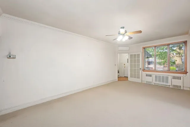 an empty room with chandelier fan and windows