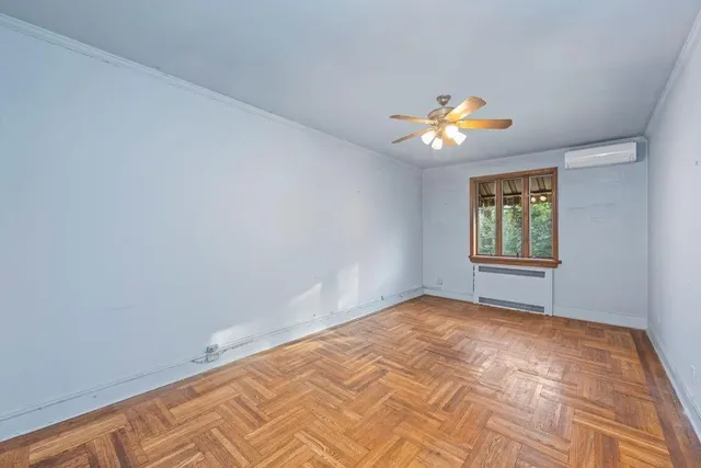 a view of an empty room with window and chandelier fan