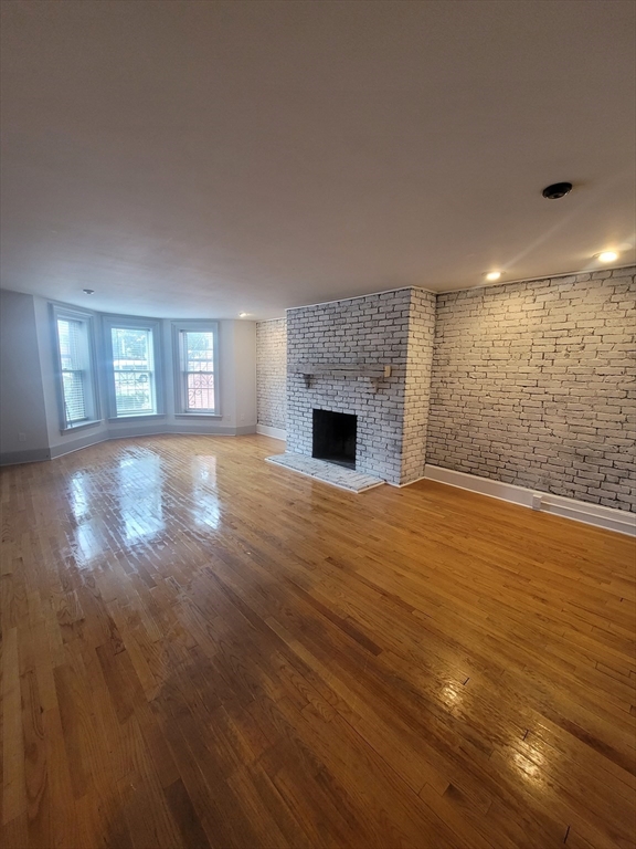 74 Temple Street, Unit 1 Springfield, MA 01105 - Photo 3 of 11 an empty room with wooden floor fireplace and windows