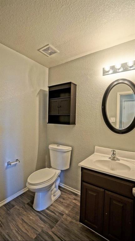 12005 Arbor Lake Road Rhome, TX 76078 - Photo 10 of 22 Half bathroom with a textured wall, a textured ceiling, vanity, and wood finished floors